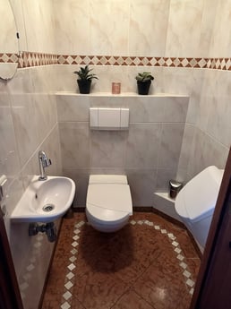 Toilet with urinal with sink and towel and soap, always toilet paper available.